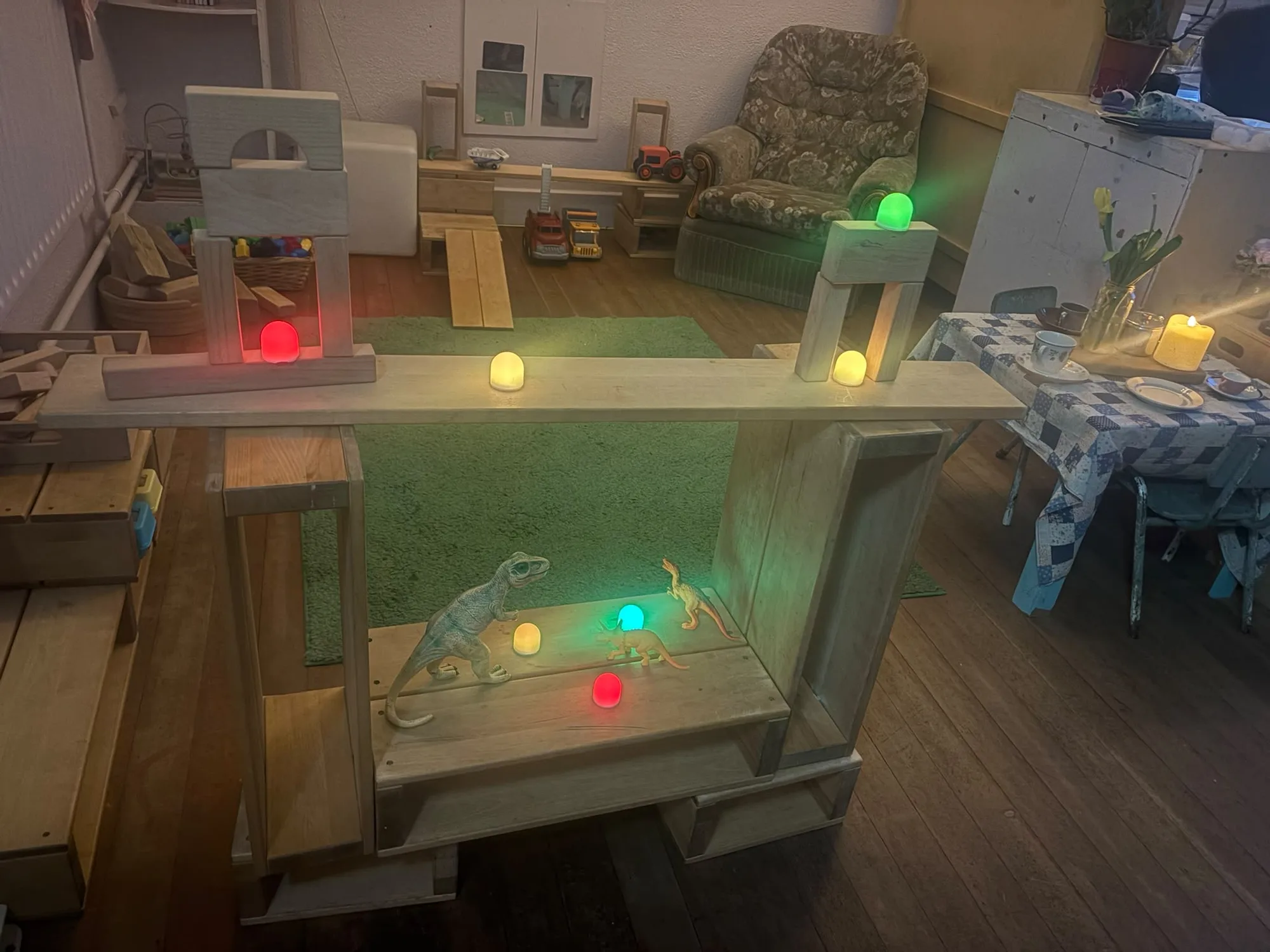 A playroom with small tables, shelves and coloured light